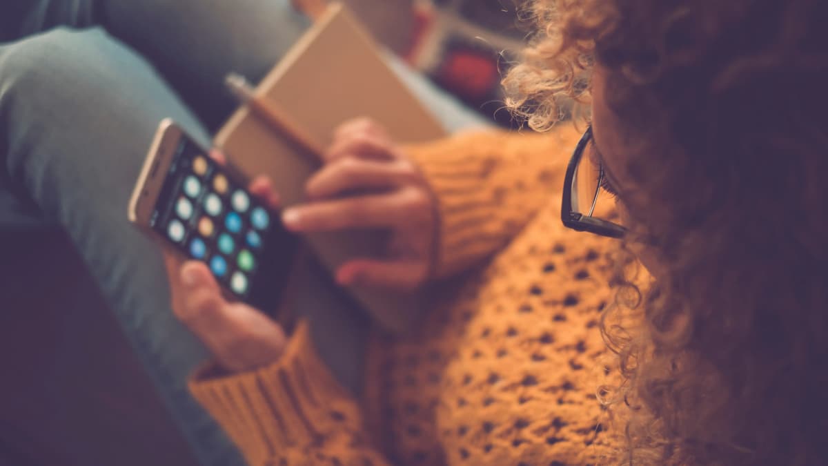 Woman with curly hair and glasses using her smartphone.